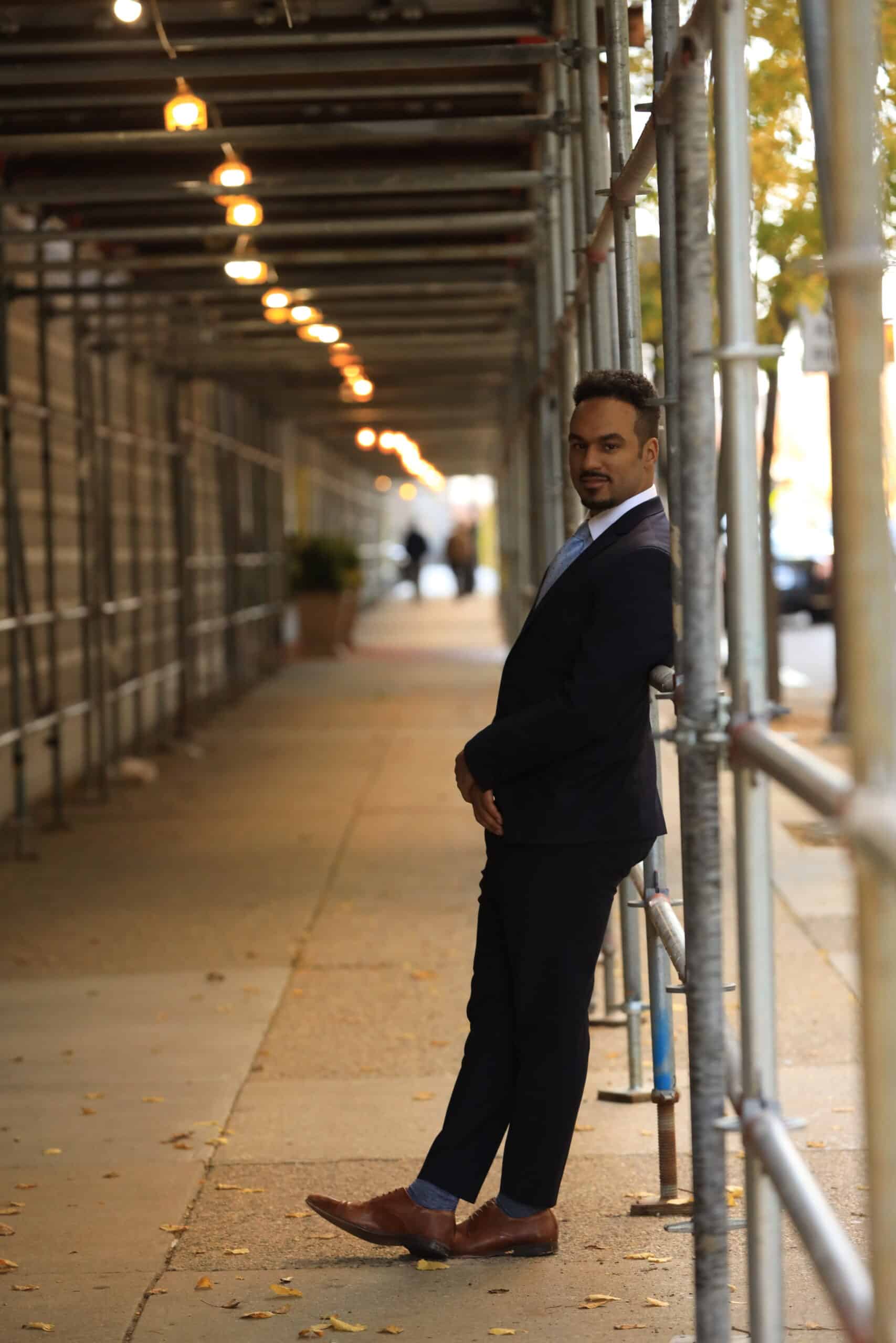 A suit-clad man leaning against a pole, representing an employment lawyer.