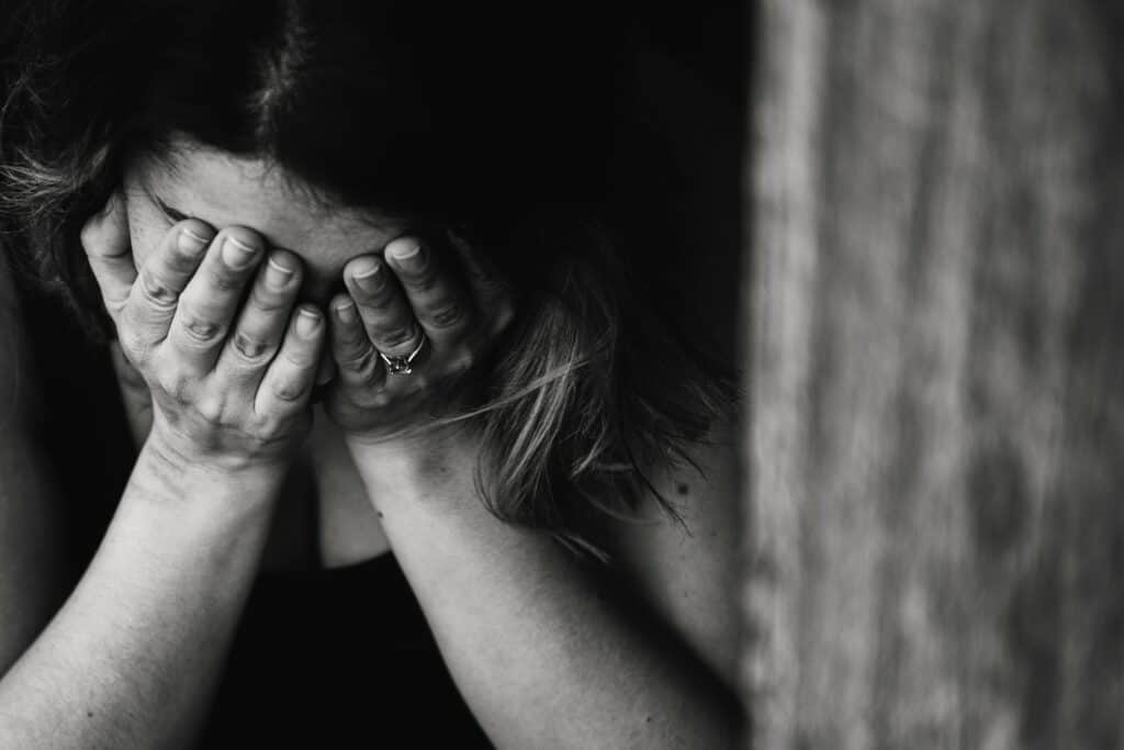 A woman covering her face with her hands.
