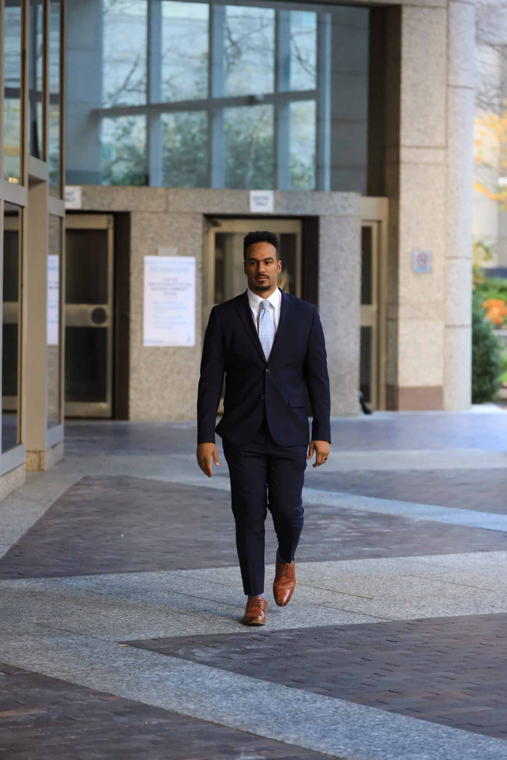 A lawyer in a suit walking in front of a building.