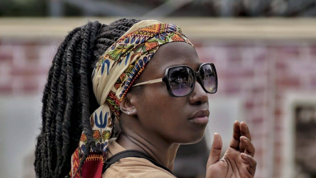 A woman with dreadlocks wearing sunglasses and a head scarf.