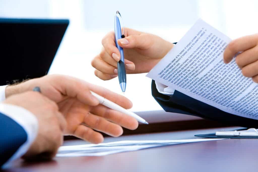 Two businessmen signing a document at a table.