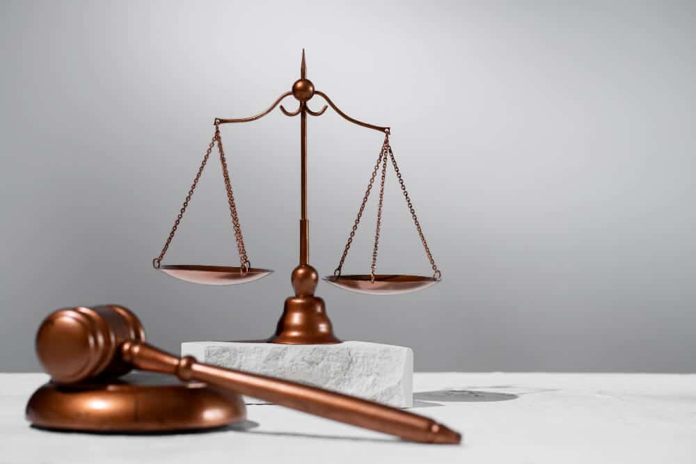 Bronze scales of justice and a gavel on a light gray surface, symbolizing law and fairness.