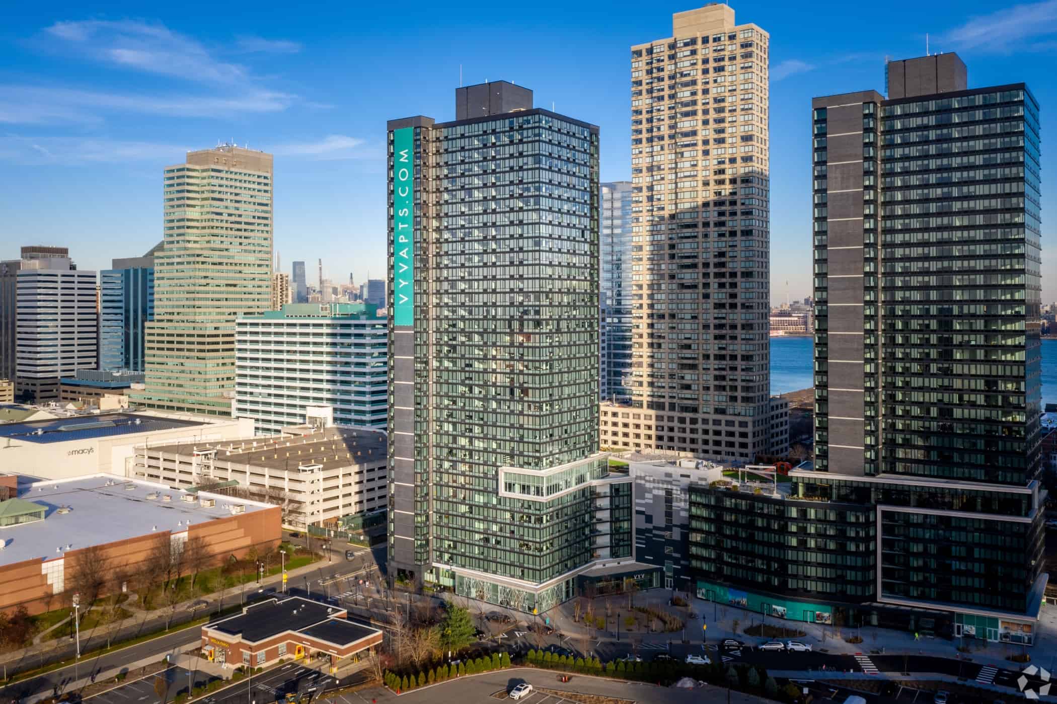 The aerial view showcases modern high-rise buildings in the city, with a river winding peacefully in the background. It's a clear day, an inspiring scene that mirrors the aspirations of an NJ employment lawyer navigating the complexities of urban professional life.