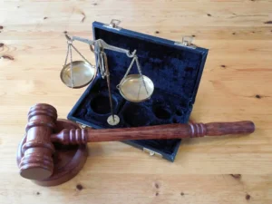 A wooden gavel and block rest beside a set of brass balance scales in an open black case on a wooden surface, symbolizing the pursuit of justice as seen in the recent Civil Rights Lawsuit Filed Against the City of Philadelphia.