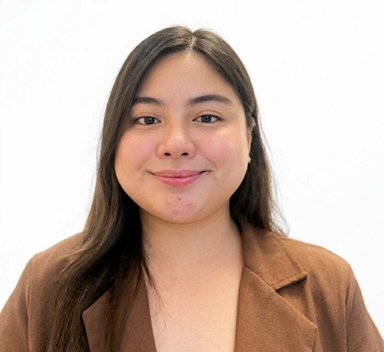 Shannen Perez, a woman with long dark hair wearing a brown blazer, smiles slightly while facing the camera against a plain white background.