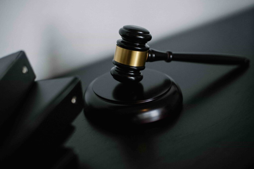 A wooden judge’s gavel rests on a sound block on a dark surface, hinting at the serious cases a discrimination lawyer in New Jersey might handle, with black folders partially visible in the background.
