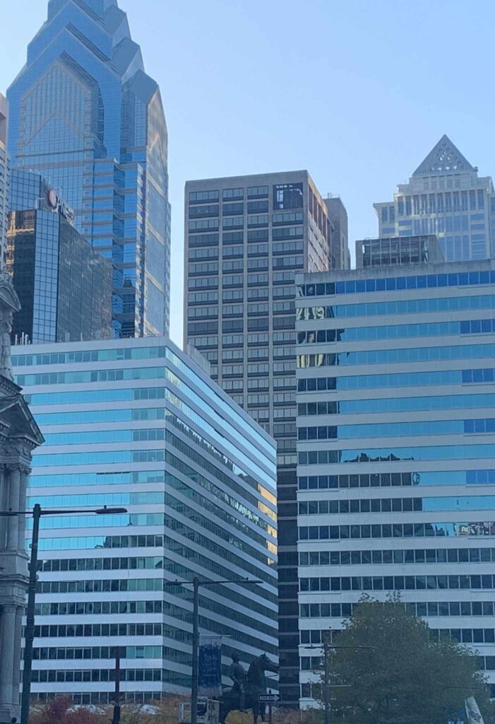 A group of modern office buildings with reflective glass windows stands in a cityscape under a clear blue sky, reminiscent of the sleek professionalism represented by The Lacy Employment Law Firm.
