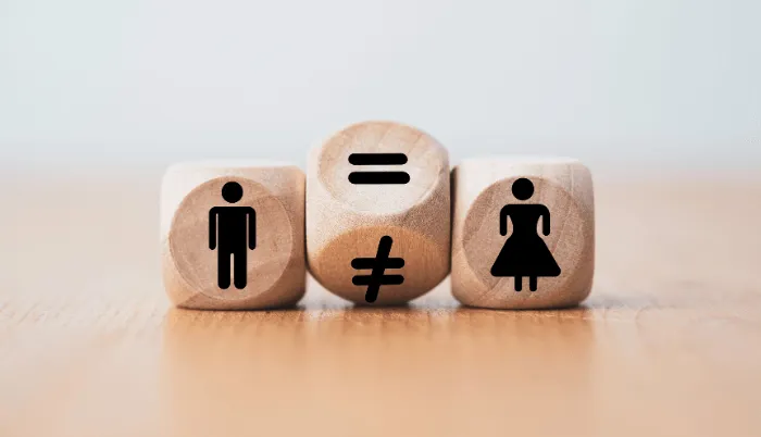 Three wooden blocks display symbols: a man, an equal sign, a not equal sign, and a woman, reflecting gender equality and inequality—key issues often addressed by a Gender Discrimination Attorney.