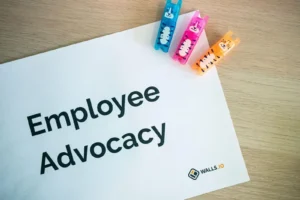A paper labeled “Employee Advocacy” lies on a wooden surface next to three colorful animal-shaped clips.